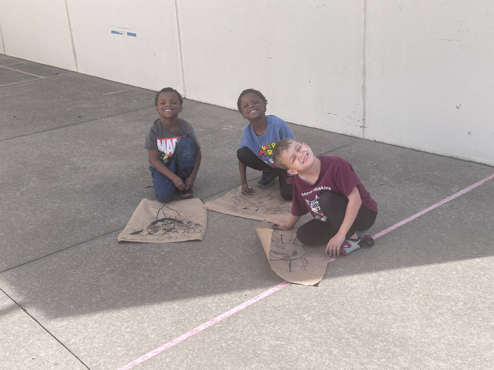 Smiling kids sitting on floor with drawings