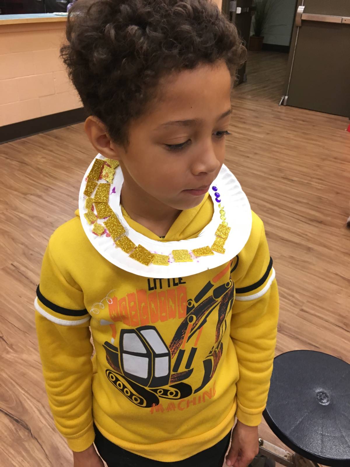 Kid wearing collar made with various art supplies
