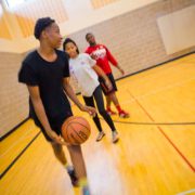 Teen dribbling basketball in gymnasium