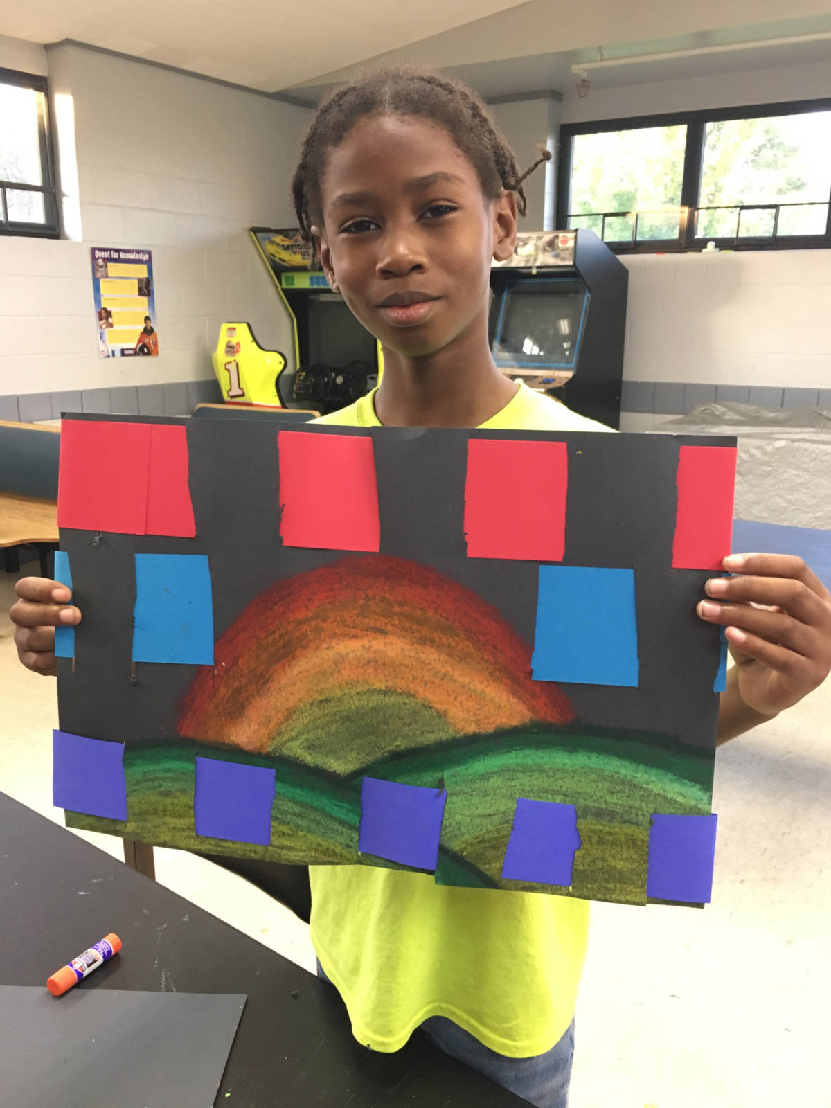 Kid holding up drawing of rainbow